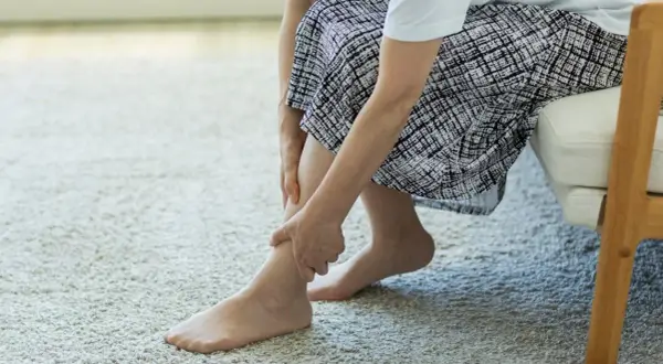 Kobieta masuje bolącą łydkę. Czy Diclovit na co pomoże złagodzić ból?