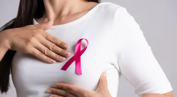 Kobieta z różową wstążką na piersi, symbolem walki z rakiem piersi. Leczenie tamoxifenem daje nadzieję.
