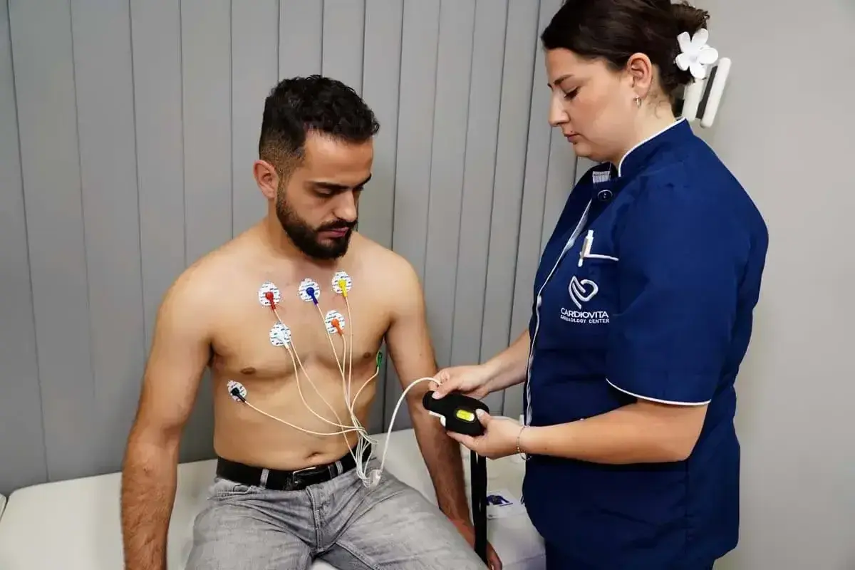 Pacjent z elektrodami EKG na klatce piersiowej, pielęgniarka podłącza urządzenie. To badanie, które odpowiada na pytanie: holter co to jest.