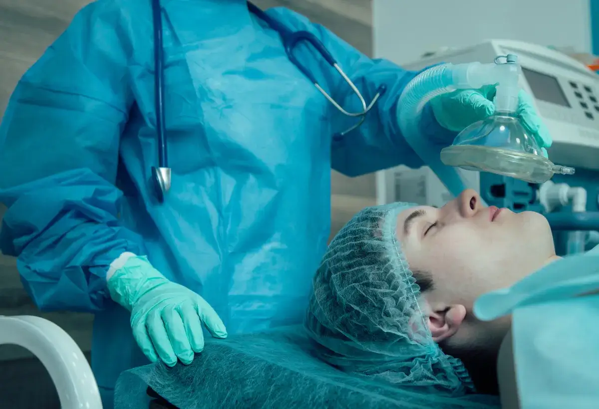 Anestezjolog podaje pacjentowi propofol przez maskę tlenową.