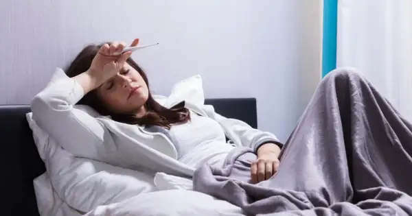 Kobieta z gorączką mierzy temperaturę, marząc o ulgę, którą może przynieść Biseptol 960.