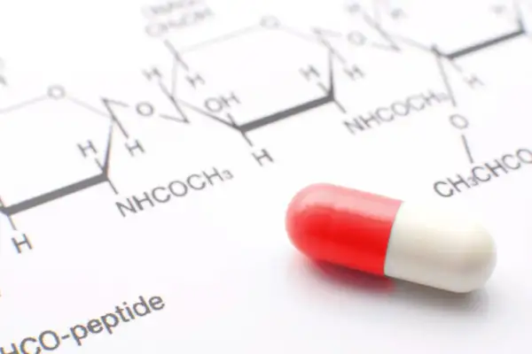 Kapsułka na tle wzoru chemicznego. Może to być element testu na narkotyki lub badania leków.
